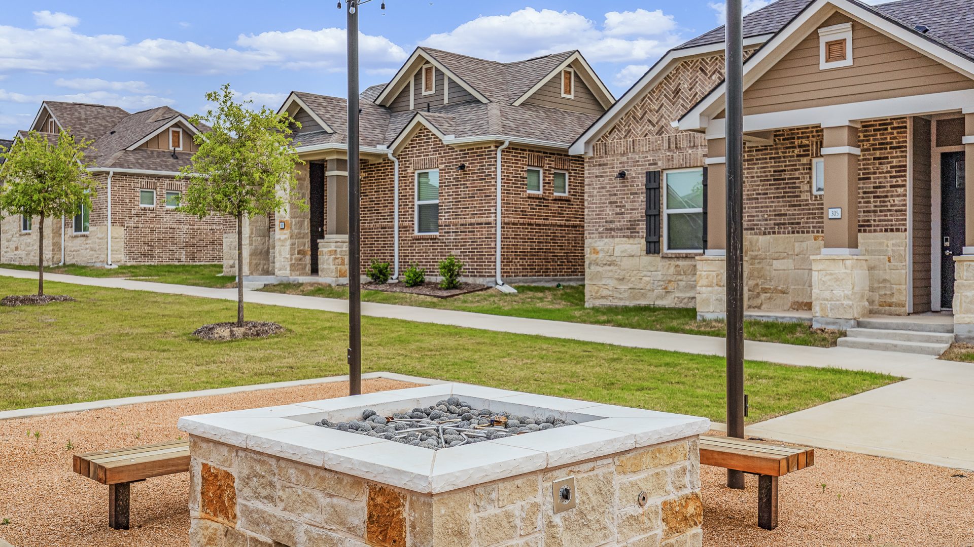 a fire pit in front of a home with benches at The VLux Stoneridge