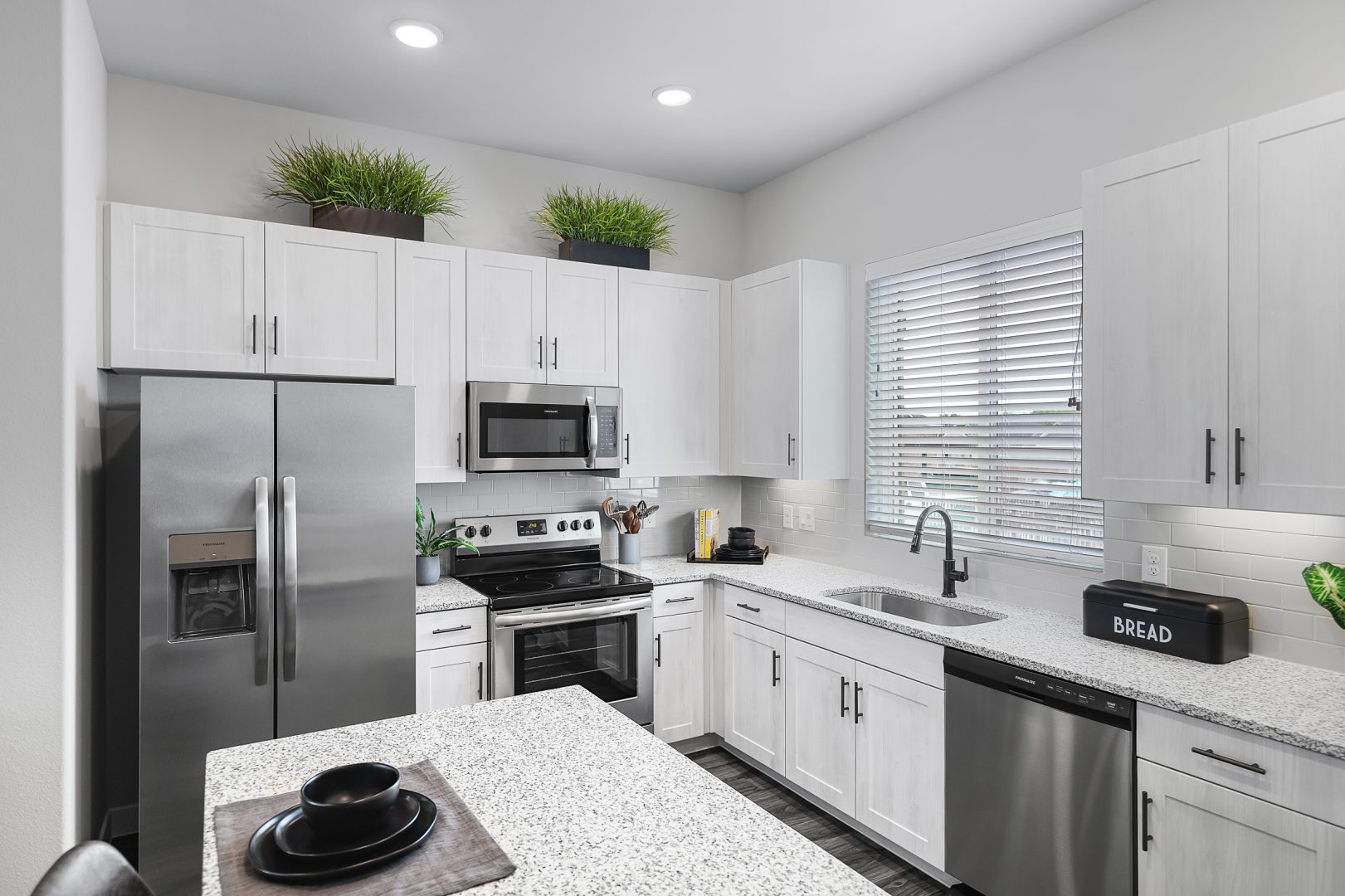 a kitchen with stainless steel appliances and white cabinets at The VLux Stoneridge