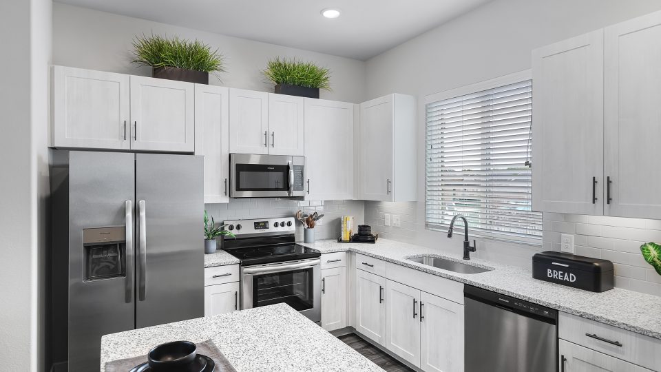 a kitchen with stainless steel appliances and white cabinets at The VLux Stoneridge