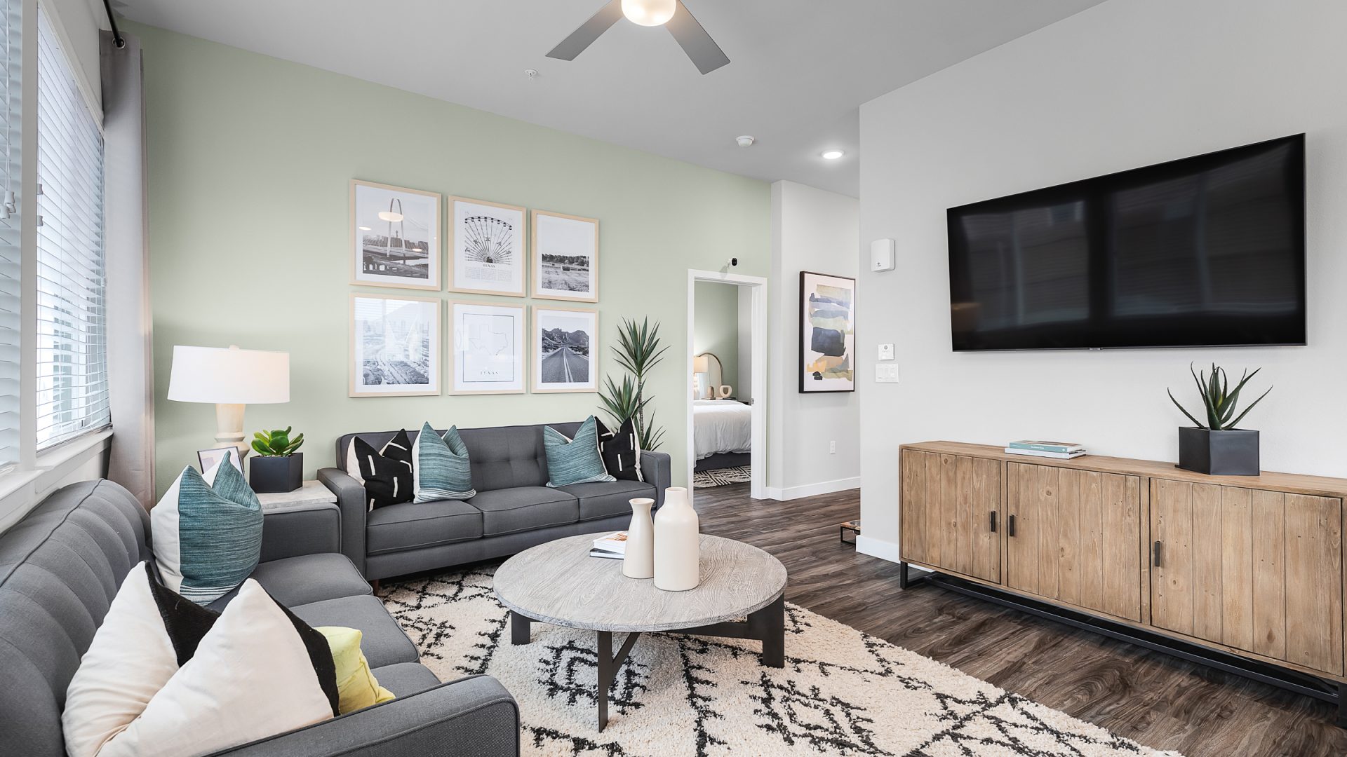 a living room with a gray couch and a flat screen tv at The VLux Stoneridge