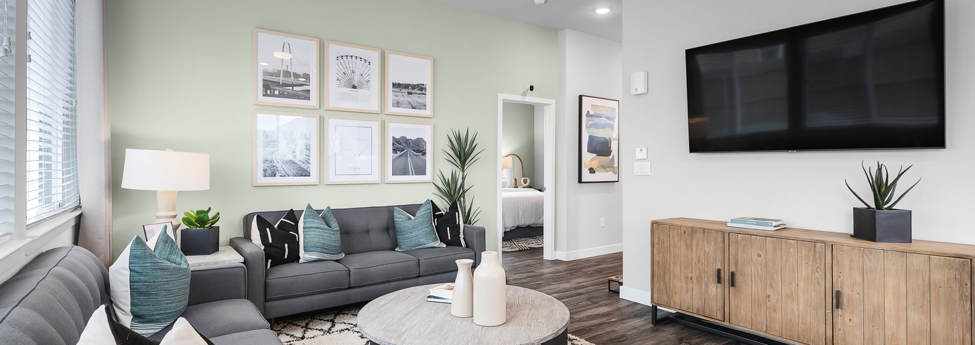 a living room with a gray couch and a flat screen tv at The VLux Stoneridge