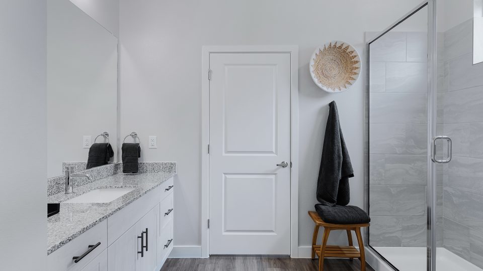 a bathroom with white cabinets and a walk in shower at The VLux Stoneridge